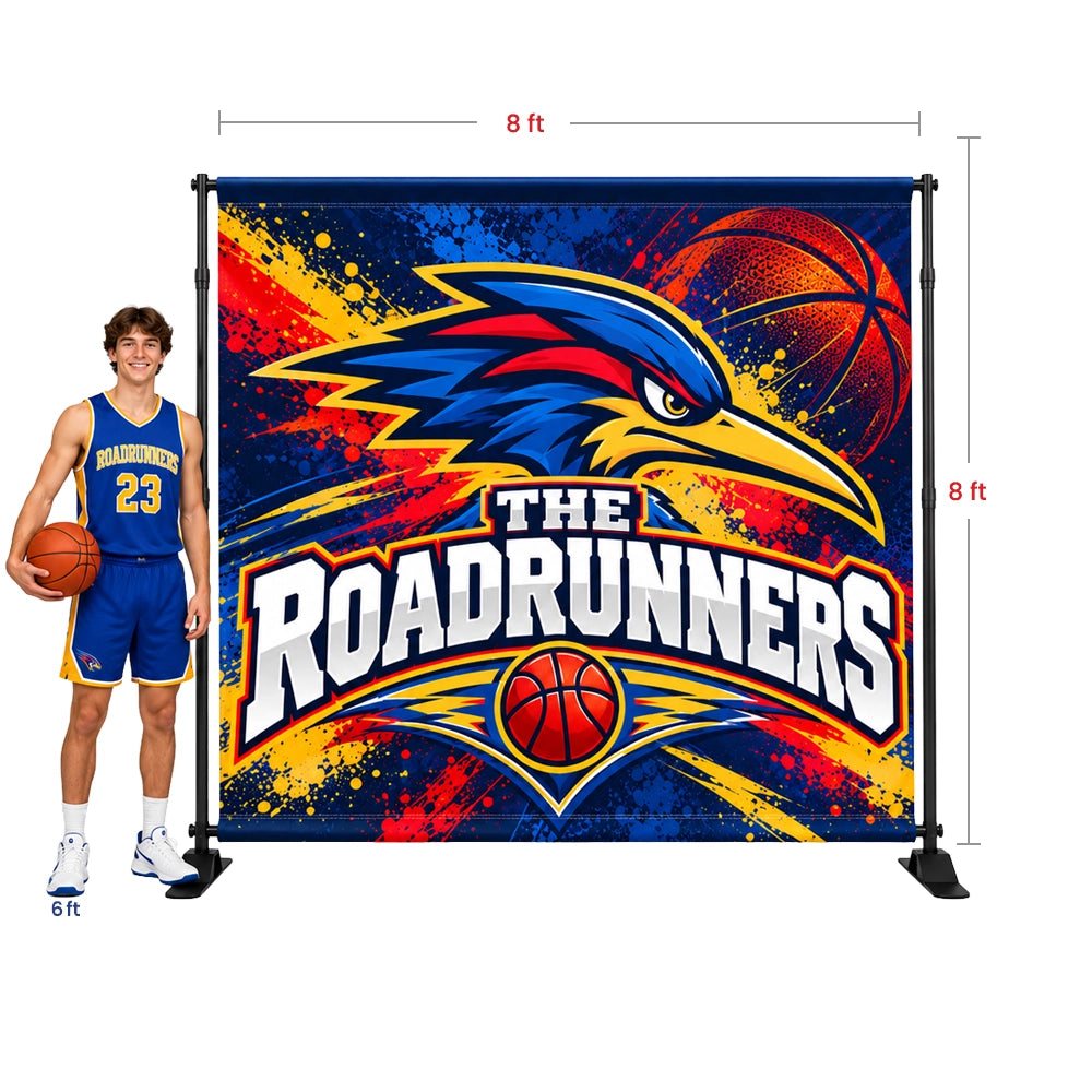 An 8x8ft basketball photo backdrop banner featuring 'The Roadrunners' team logo, shown next to a male model wearing a basketball uniform to indicate scale. The backdrop has a colorful design with a blue bird, basketball, and red/orange paint splatters on a dark blue background.