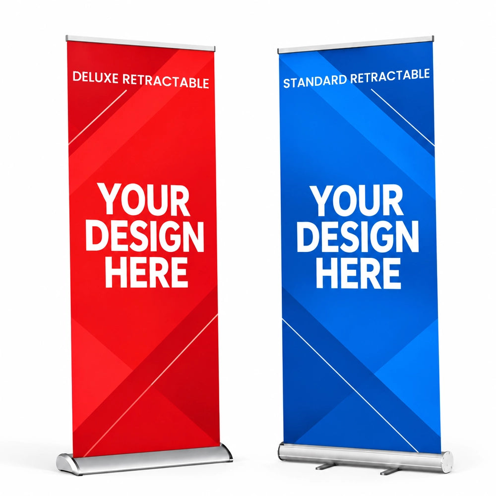 Two retractable banner stands shown on a white studio background: a red deluxe stand on the left and a blue standard stand on the right, each with large placeholder text reading 'YOUR DESIGN HERE' and smaller text indicating deluxe/standard retractable.